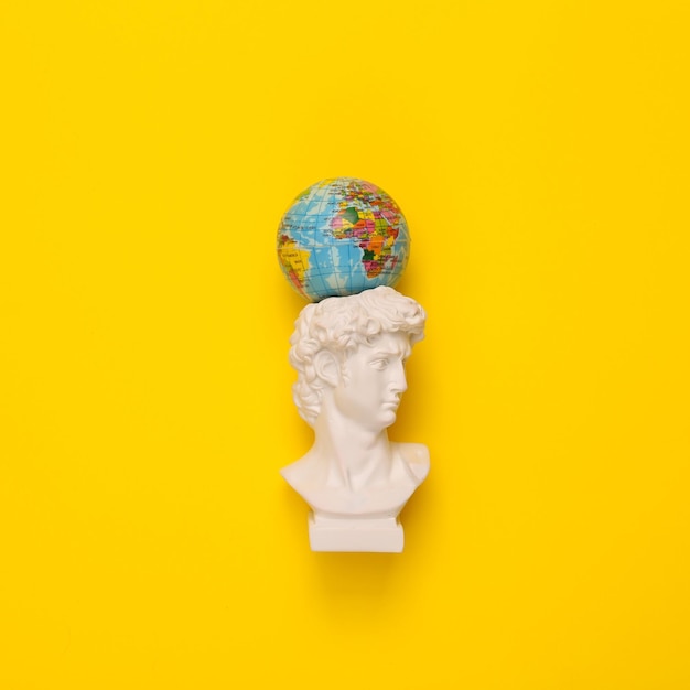 Foto antique david bust with globe on yellow background conceptual pop minimal still life creative idea flat lay