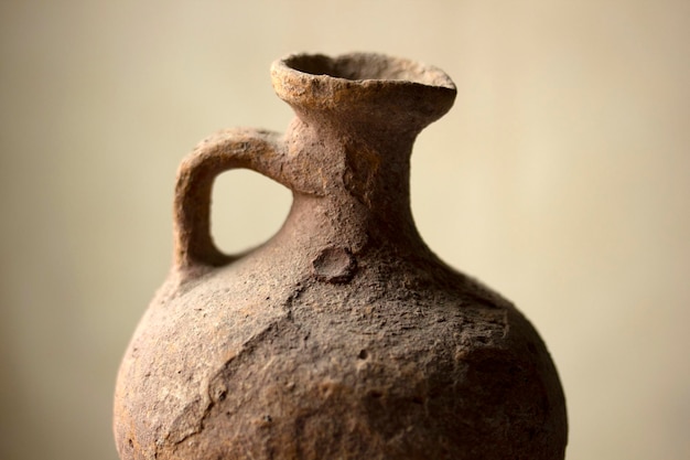 Antique earthen water pot on color background