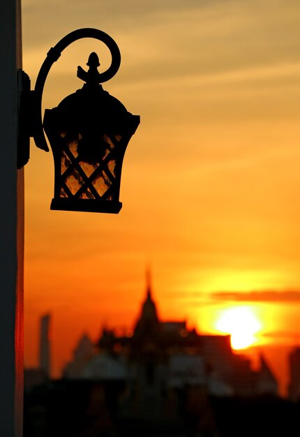 antique lamp with blurry silhouette of a temple at dawn in Bangkok