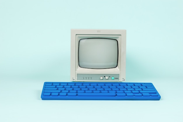 An antique monitor and a stylish blue keyboard on a light blue background.