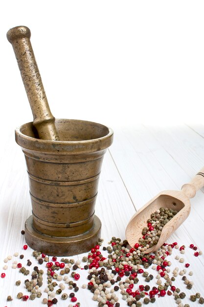 Antique mortar and pepper on white wooden background