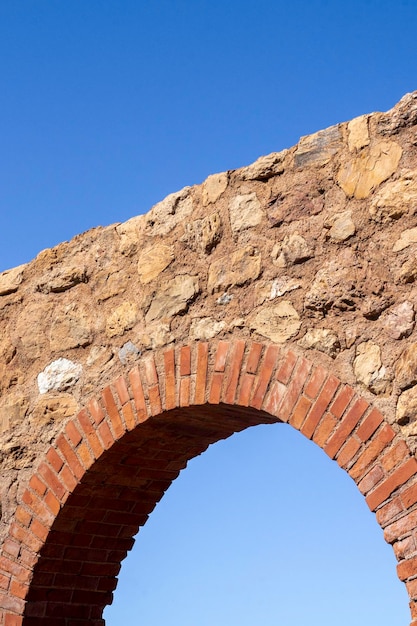 Antique old monument ruin arch architecture made with rocks and bricks with blue sky in the background