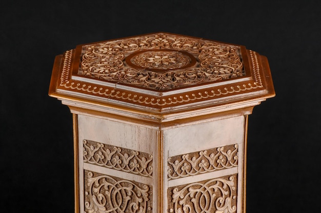 The antique oriental wooden table with the artistic carving on a black background Uzbekistan closeup