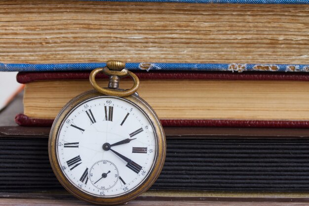 Foto antico orologio da tasca su sfondo di libri d'epoca