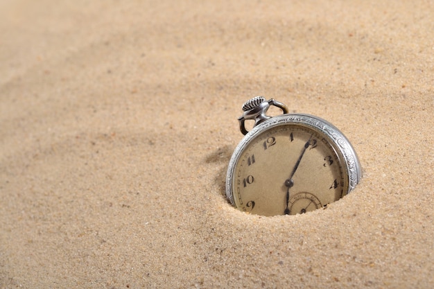 Antique pocket watch in sand