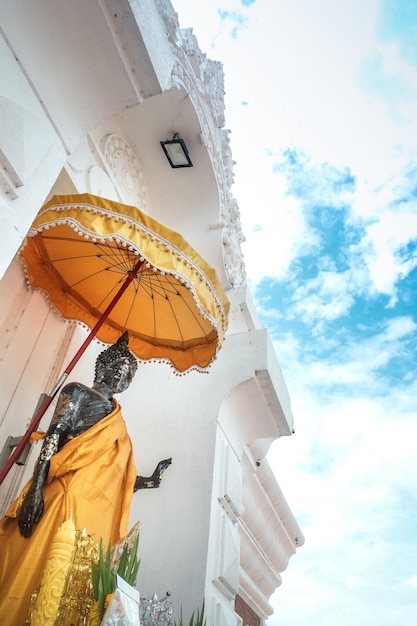 Antique standing Thai Buddha statue and blue sky