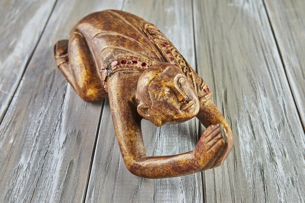 Antique statuette of praying buddha on wooden background.