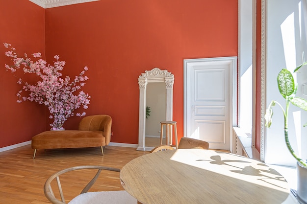 Antique vintage interior in 19th century style living room with bright red walls, wood floor and direct sunlight inside the room.