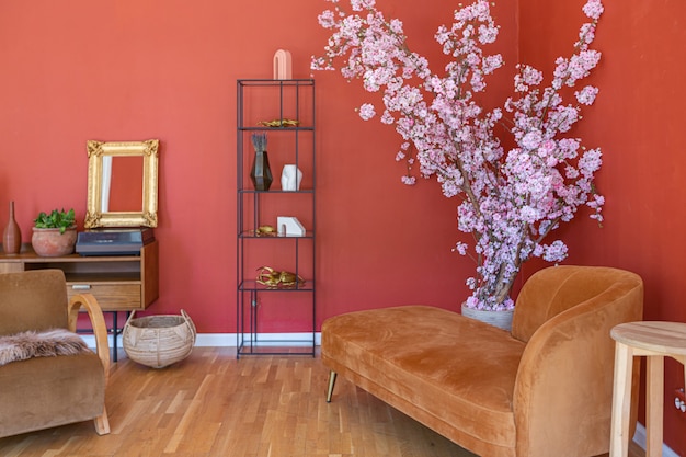 Antique vintage interior in 19th century style living room with bright red walls, wood floor and direct sunlight inside the room.