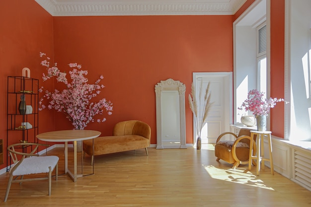 Antique vintage interior in 19th century style living room with bright red walls, wood floor and direct sunlight inside the room.