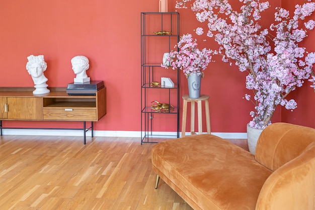 Antique vintage interior in 19th century style living room with bright red walls, wood floor and direct sunlight inside the room.