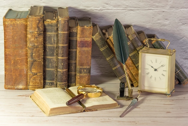 Photo antique watch along with antique books and vintage writing pen.