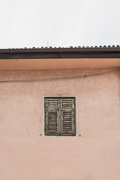 Antique wooden window with shutters on neutral pink wall Historic architecture in Italy Aesthetic summer vacation travel concept