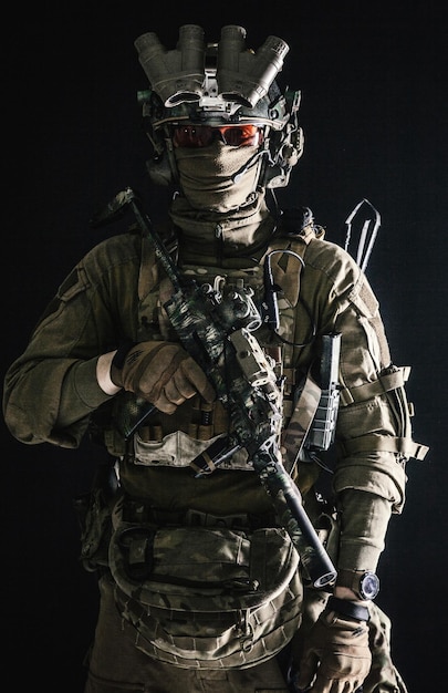 反テロリストの分隊戦闘機の軍隊エリートは戦闘服と戦術的な弾薬で兵士を強制します黒い背景にナイトビジョンデバイスの控えめなスタジオの肖像画を身に着けているミニサブマシンガン