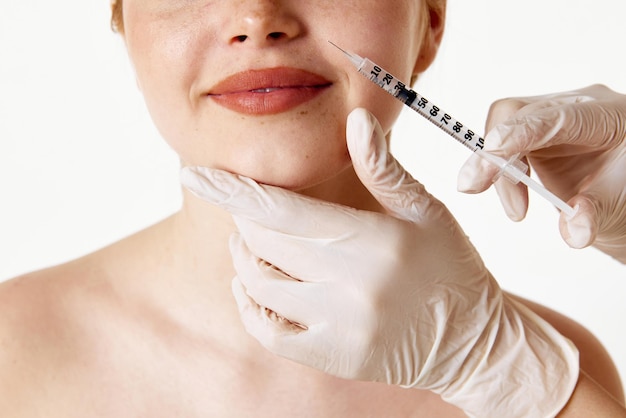 Foto cura antirughe immagine ritagliata del volto femminile con siringa che effettua l'iniezione di filler di bellezza contro