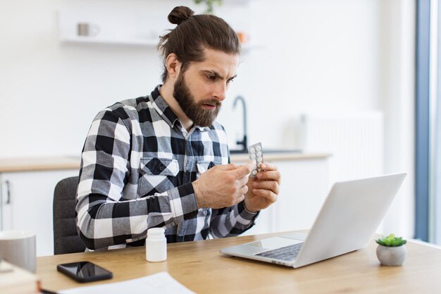 Anxious adult person holding round pills while having online conversation