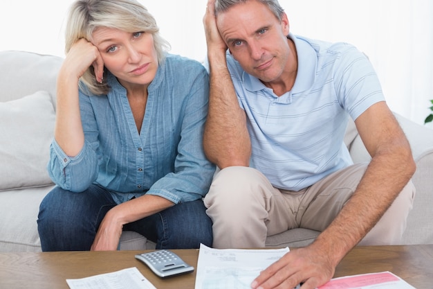 Anxious couple going over bills looking at camera