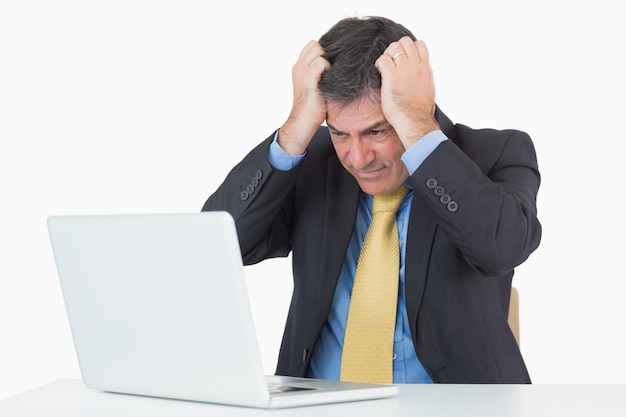 Anxious man sitting at his desk with a laptop