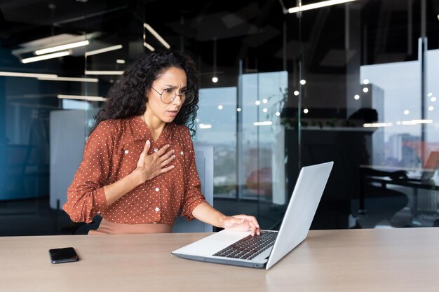 Anxious and scared business woman working inside office hispanic woman panic attack and breathing