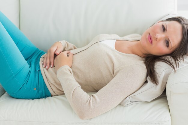 Anxious and sick woman lying on sofa