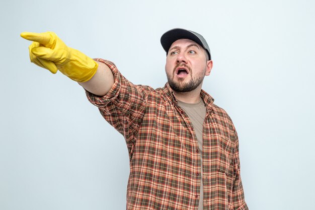 Anxious slavic cleaner man with rubber gloves looking and pointing at side 