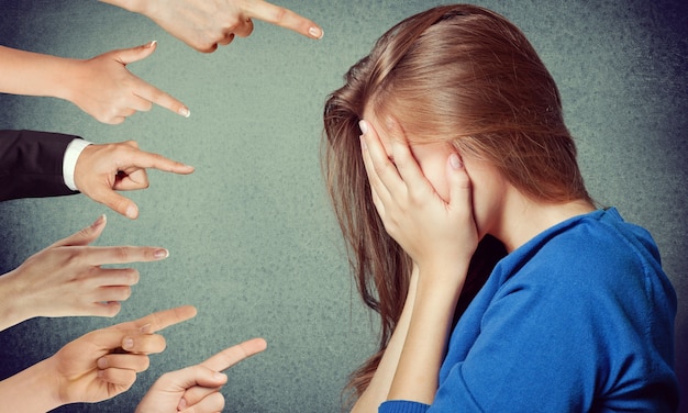 Anxious woman judged by different hands. Concept of accusation of guilty girl.