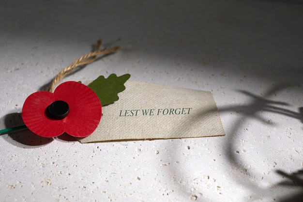 Photo anzac day australian and new zealand national public holiday or remembrance day red poppy on biege s...