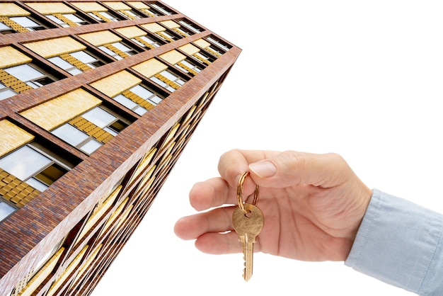 Apartment key in a man's hand. Brass house door lock key. Modern building, view from below. Architecture in modern city. Sale and rental of real estate.