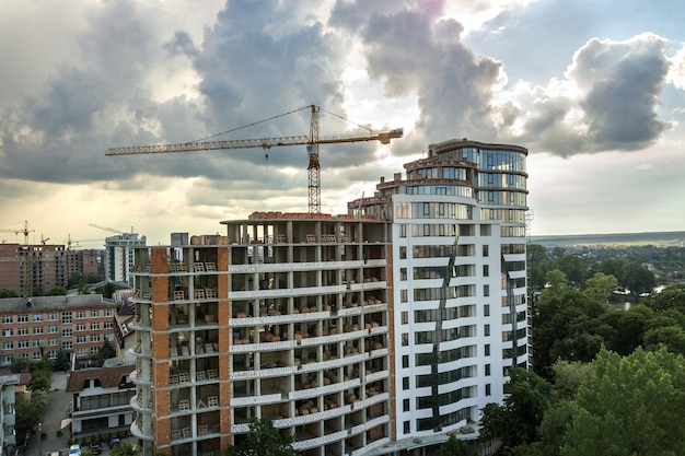 Apartment or office tall building under construction. Brick walls, glass windows, scaffolding and concrete support pillars.