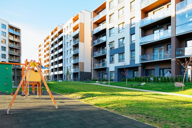 Apartment residential house facade architecture with children playground and outdoor facilities. Blue sky on background.