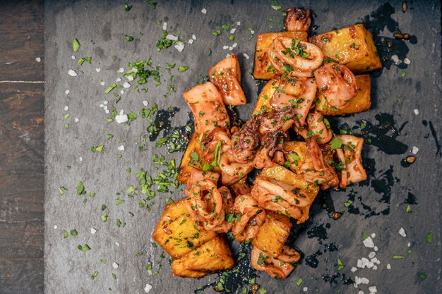 Aperitief of typisch Spaanse tapa baby-inktvis met knoflook en aardappelen geserveerd op een langwerpige witte