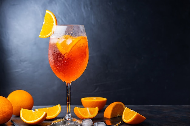 Aperol spritz cocktail and bar accessories. Italian aperol spritz cocktail and a sliced orange on a dark background. Summer cocktail aperol spritz on a slate board