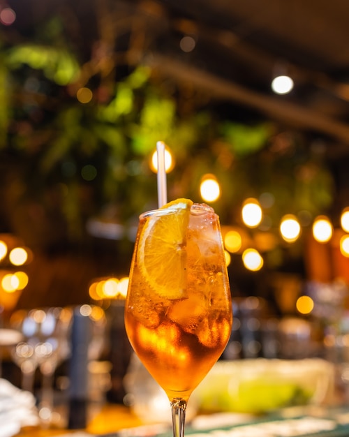 Aperol spritz cocktail in glass on wooden table on dark background in cafe.