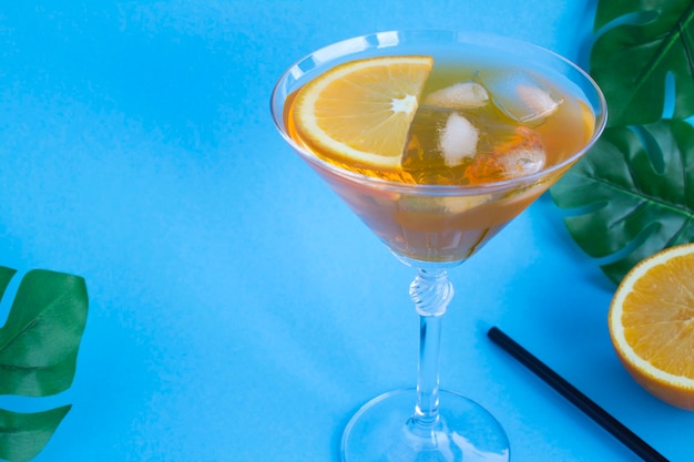 Foto aperol spritz cocktail nel bicchiere da martini sullo sfondo tropicale. copia spazio. avvicinamento.