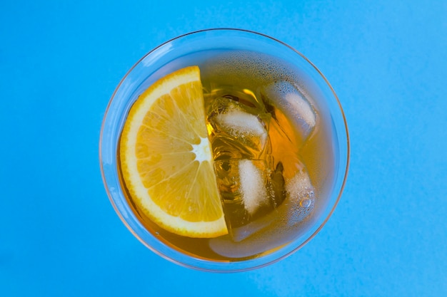 Aperol spritz cocktail or orange cocktail in martini glass in the center of the blue table. Top view. Copy space. Closeup.