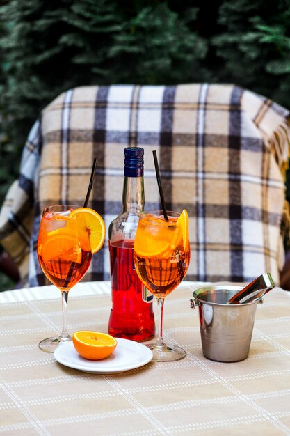 Aperol spritz cocktailglas plaid tafel laat zon oranje ijsemmer schaduw zonlicht