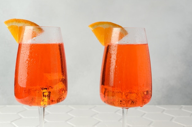 Aperol spritz cold summer cocktail with aperitif prosecco ice and slice of orange in a glass on the white background Copy space for text