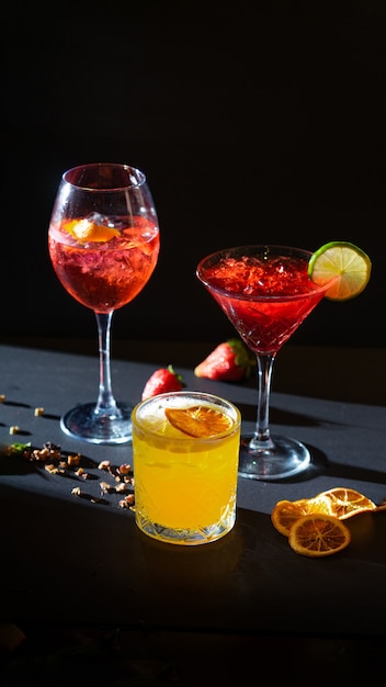 Aperol spritz en rode en gele aperitiefcocktails in glas met ijs op zwarte achtergrond