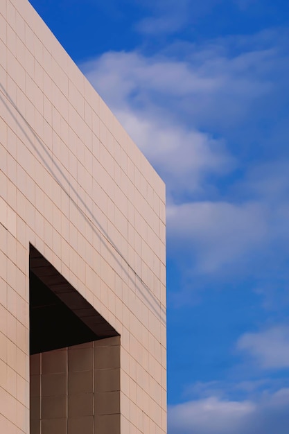 Apertures window on gray tile wall of office building against white clouds on blue sky