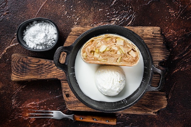 Apfelstrudel strudel with cinnamon, powdered sugar and vanilla ice cream in a pan