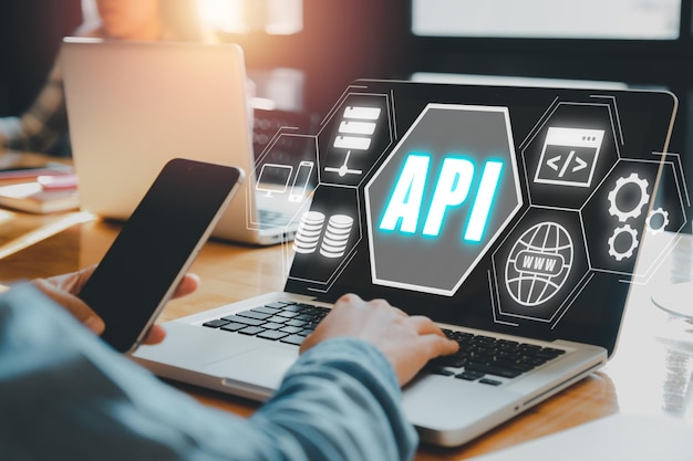 Интерфейс программирования приложений API Женщина, использующая ноутбук с экраном VR Икона API на офисном столе Инструмент разработки программного обеспечения Современная технология Интернет и сетевая концепция
