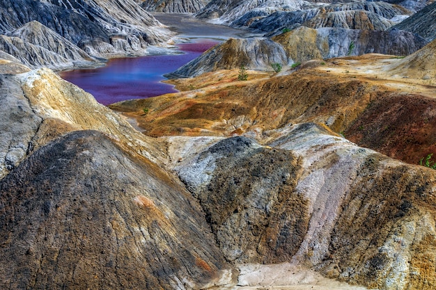 Apocalyptic landscape like a planet Mars surface. Fantastic view of crimson red lake. Solidified red-brown black Earth surface. Barren, cracked and scorched land. Global warming concept