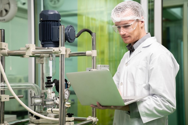 Apothecary scientist recording data from CBD oil extractor in laboratory