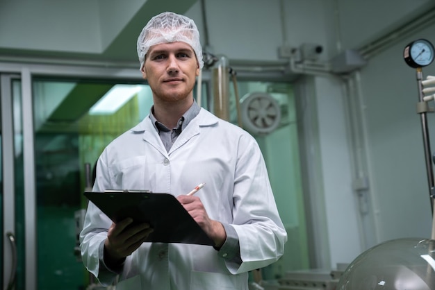 Apothecary scientist recording data from CBD oil extractor in laboratory