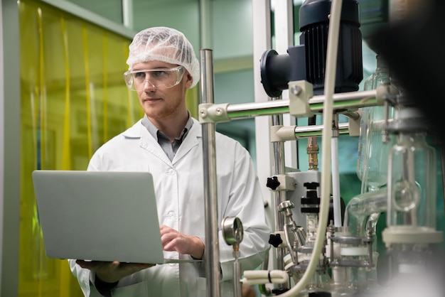 Apothecary scientist recording data from CBD oil extractor in laboratory