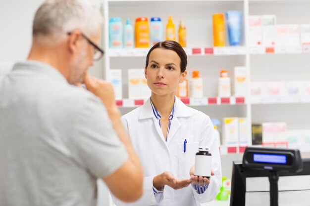 Foto farmacista che mostra il farmaco a un anziano in farmacia