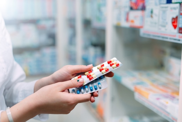 Apotheker die medicijndoos en capsuleverpakkingen in apotheekdrogisterij houdt.