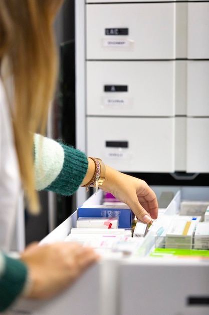 Apotheker in witte jas die medicijnen in een witte ladekast legt