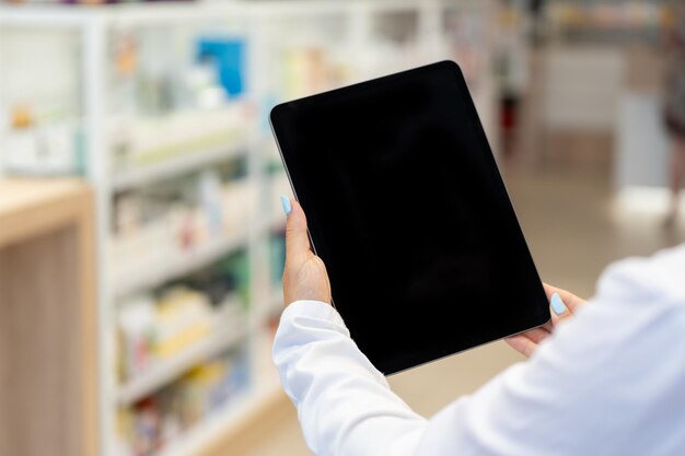 Apotheker kijkt naar het zwarte scherm van een digitaal tablet in de apotheek