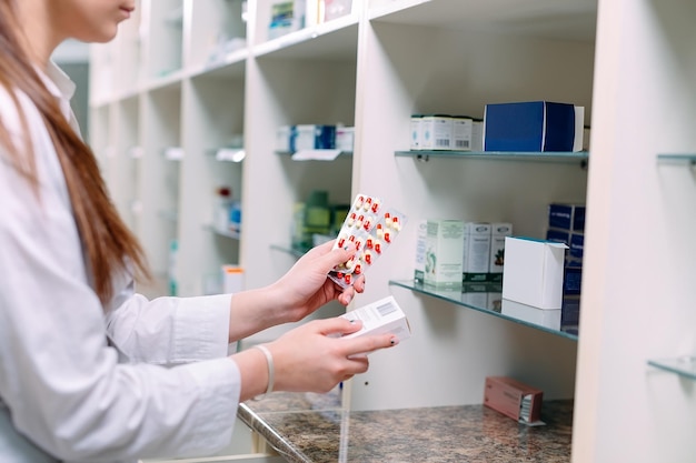 Apotheker met medicijndoos en capsuleverpakkingen in apotheekdrogisterij.